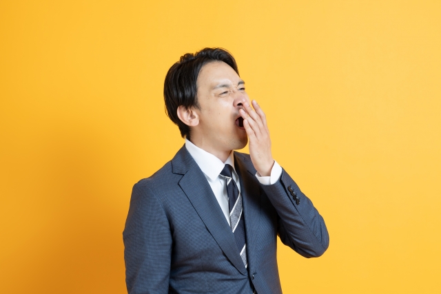 あくびをするスーツ姿の男性
